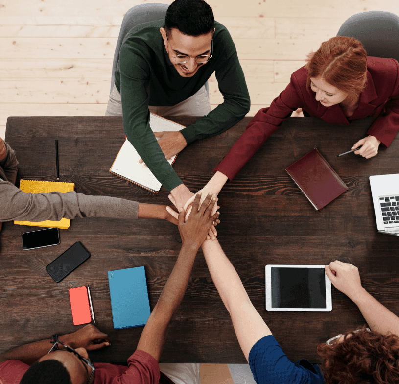 Team joining hands over a work table